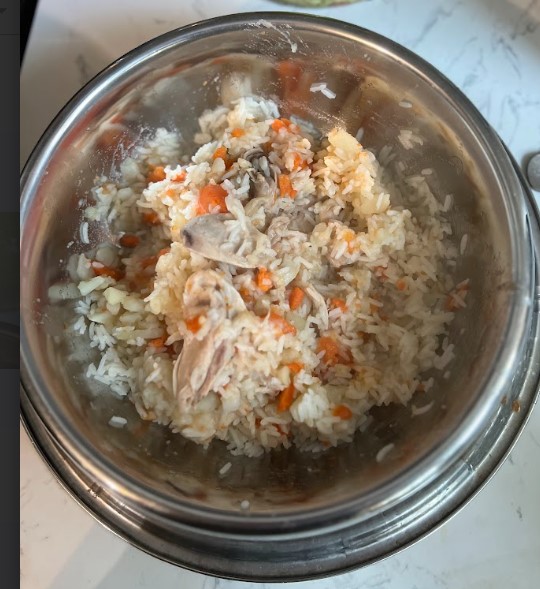 A bowl of dog-friendly food consisting of: carrots, chicken, and rice.